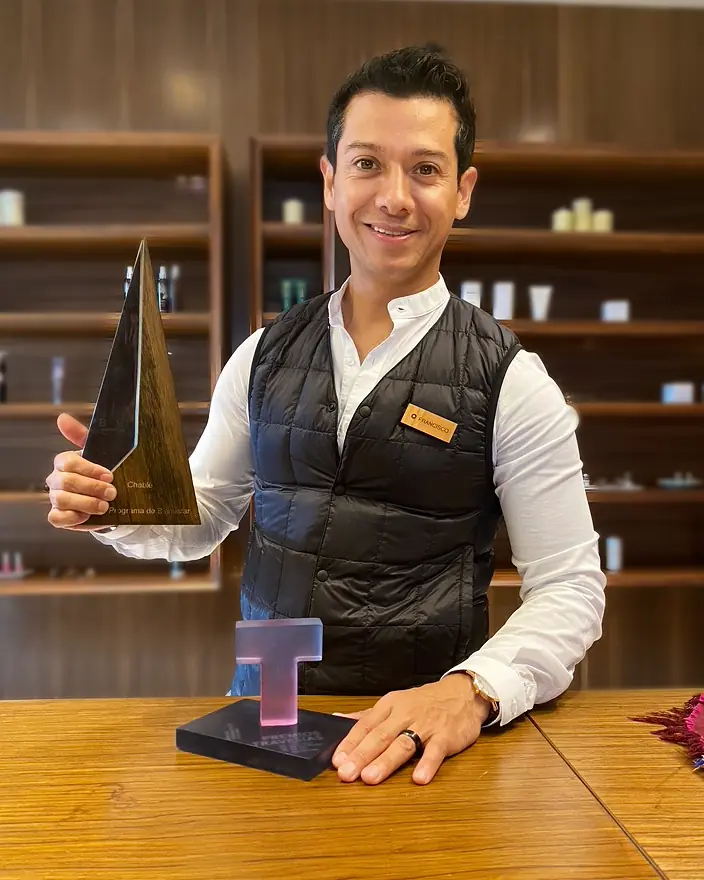 Francisco Lugo holding a wellness program award in the Chablé Yucatán spa boutique.