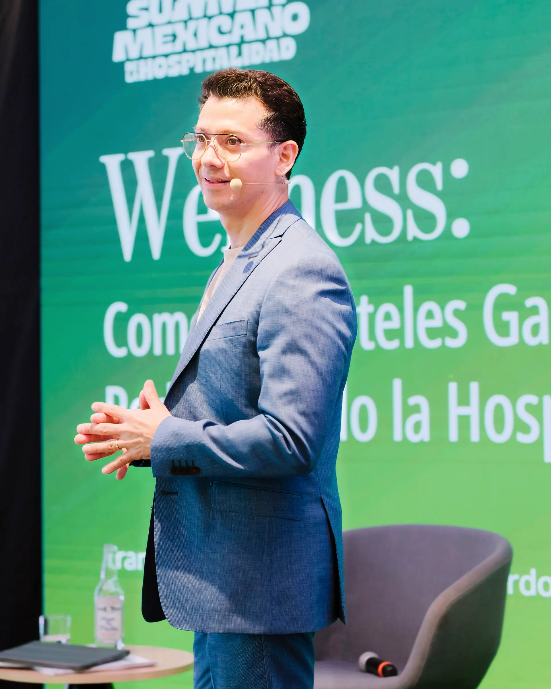 Francisco Lugo on stage at the Summit Mexicano de la Hospitalidad, in front of the session screen.