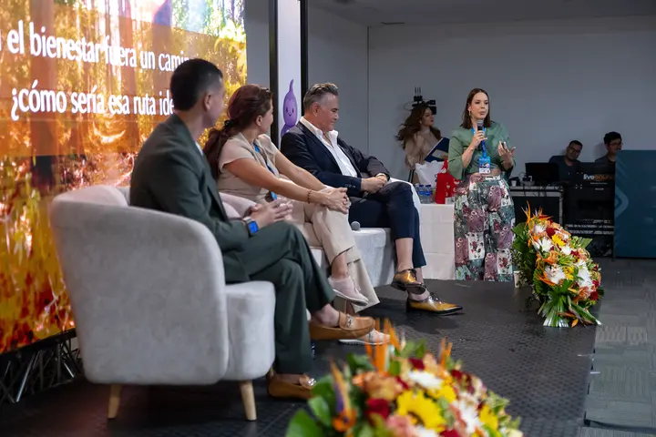 Francisco seated on a panel with other speakers in front of a forest projection.