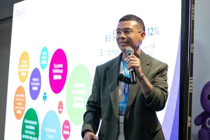 Francisco presents in front of a screen of wellness market figures.