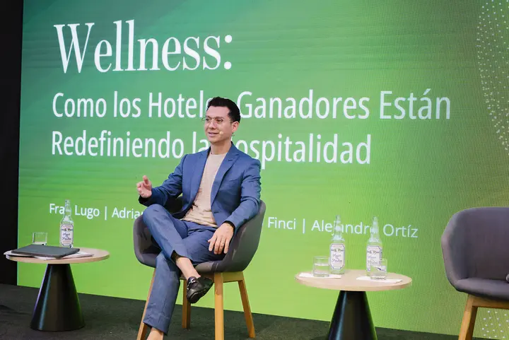 Francisco seated on stage during a panel at Summit Mexicano de la Hospitalidad.